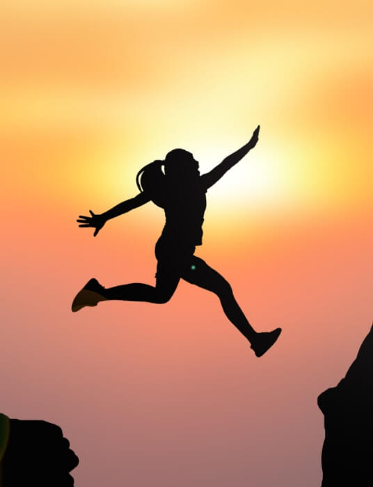 woman_hiking_jumping_sunset
